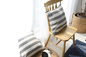 Close-up of striped cotton linen cushion cover on a wooden chair in a bright cozy room