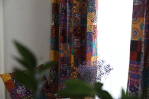 Dettaglio di tende patchwork bohémien con motivi paisley colorati e cuscini coordinati