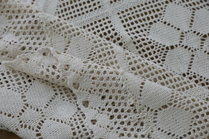 Close-up of handmade crochet lace fabric with intricate floral cutout patterns