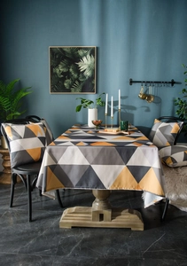 Detail of geometric table cloth and cushions in grey and yellow for modern dining room