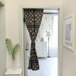 Black and white geometric jacquard cafe curtain with tie-back design in a rustic doorway