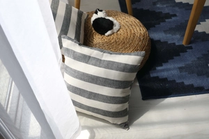 Detail of striped throw pillow case with natural linen texture next to a white curtain