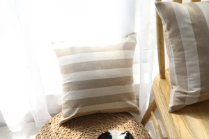 Detail of striped cushion cover in beige and cream linen texture on a woven mat