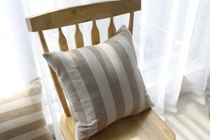 Detail of striped cotton linen cushion cover in beige and white on a wooden chair
