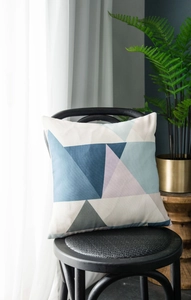 Close-up of modern geometric triangle pillow on a black chair in a cozy living room