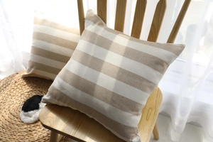 Detail of striped throw pillow cover fabric texture on a wooden chair with cozy lighting