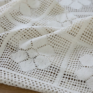 Retro handmade crochet tablecloth with floral hollow patterns on a wooden table