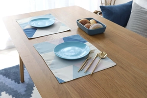 Detail of waterproof Nordic geometric placemat in blue and purple on a wooden table