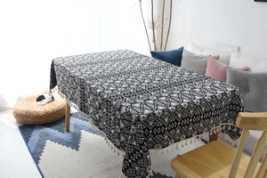 Dettaglio della tovaglia geometrica bohémien bianca e nera con eleganti nappe in cotone beige