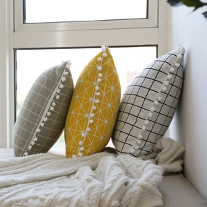 Linen lumbar pillows with pom-poms featuring geometric, plaid and olive green patterns