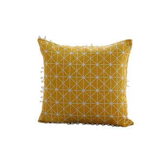 Square yellow lumbar pillow with white geometric mesh pattern and pom-pom trim