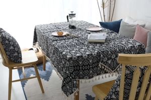 Dettaglio tovaglia nordica con motivi geometrici neri e nappe color crema in cotone