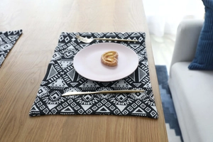 Detail of Nordic jacquard placemat with black and white geometric patterns on a wooden table