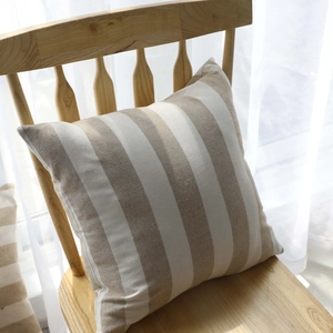 Striped cotton linen decorative pillow cover on wooden chair with soft sunlight