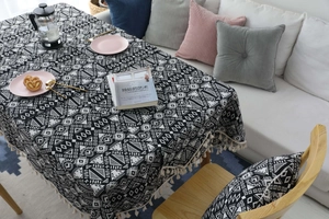 Dettaglio del motivo geometrico bianco e nero sulla tovaglia in lino con nappe decorative