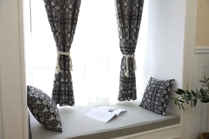 Detail of bohemian geometric black and white curtains with cream cotton tassel tiebacks