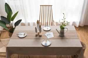 Detail of beige linen tablecloth featuring brown lace patchwork and elegant fringe edges