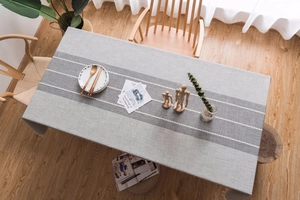 Detail of gray linen-textured tablecloth with embroidery and fringe in Nordic style