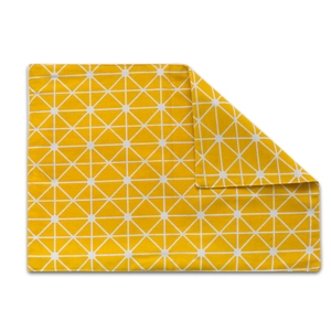 Detail shot of yellow fabric placemat with white geometric patterns and folded corner