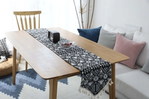 Dettaglio di un runner da tavola nordico con motivi geometrici e nappe in cotone
