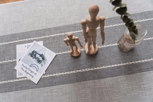 Detail of grey linen table runner with white wheat embroidery and fringed edges