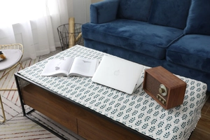 Détail de nappe nordique en lin avec motifs de feuilles vertes et pompons blancs