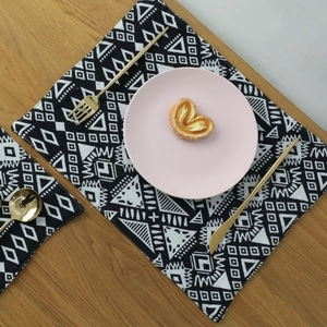 Nordic geometric woven placemat set with black and white ethnic patterns on wood table