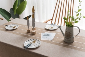 Close-up of burlap table runner with white lace edges on beige linen tablecloth