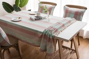 Detail of striped waterproof tablecloth with elegant beige tassel fringe on edge