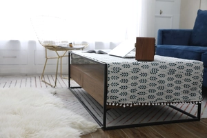 Détail d'un chemin de table nordique en coton et lin avec feuilles bleues et pompons