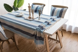Close-up of blue and beige striped linen tablecloth with decorative tassel fringes and pillows