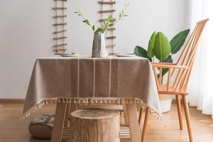 Close-up of rustic linen tablecloth featuring textured embroidery and elegant fringe details