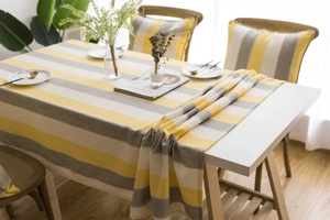Detail of waterproof striped tablecloth and cushions in modern yellow and grey home decor