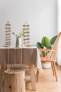 Detail of linen table runner with white woven lines and decorative tassel trim fringes