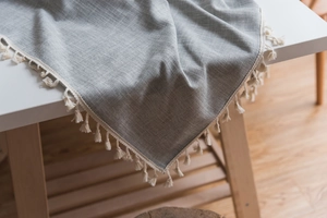 Detail of grey linen-like tablecloth featuring delicate cream tassel fringe edging