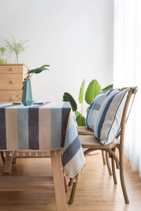 Détail de nappe imperméable à rayures bleues avec franges élégantes et coussins assortis