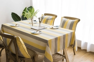 Close-up of yellow and grey striped waterproof linen tablecloth and matching chair cushions
