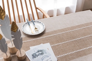 Close-up of linen table runner with beige patchwork and white woven hollow lace details