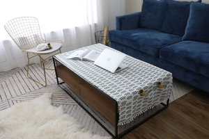 Détail d'une nappe nordique en coton et lin avec motif de feuilles et franges pompons