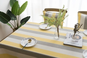 Close-up of waterproof striped linen tablecloth in yellow, grey, and white tones