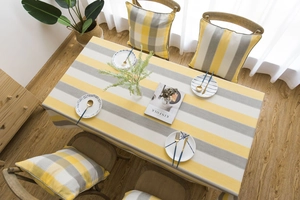 Detailed top view of a waterproof yellow and grey striped tablecloth on a dining table