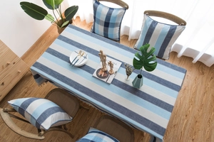 Détail de nappe rayée bleue imperméable avec bordure à franges et coussins assortis