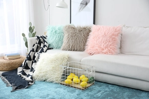 Close-up of fluffy faux sheepskin pillow covers in pastel colors on a white sofa