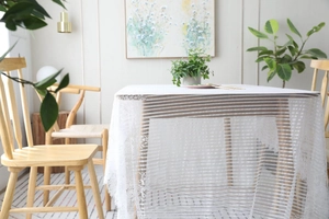 Vue détaillée de la nappe en dentelle blanche avec broderies florales et texture maille