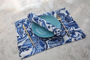 Close-up of blue floral table mat and napkin set on marble surface with cutlery