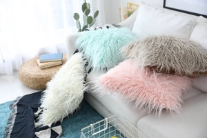 Detail view of plush faux fur decorative pillows in pastel colors on a white sofa