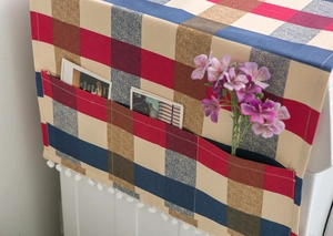 Detail of Nordic plaid dust cover with storage pockets and white pompom fringe trim