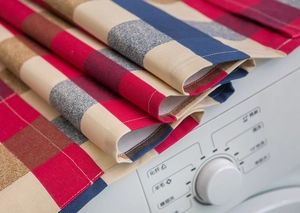 Detailed macro view of checkered linen fabric with fine stitching on a washing machine
