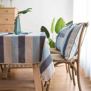 Nappe rayée bleue imperméable avec pompons et coussins assortis dans un décor de maison