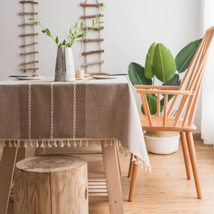 Faux linen tablecloth with beige stripes and white tassels on a wooden dining table